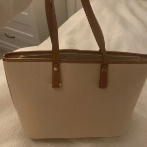 Hm väska  - Stor vit beige handväska från H&M. Använts två gånger och är i bra skick. Har dragkedja och lite små fack inuti. Skriv om ni har frågor