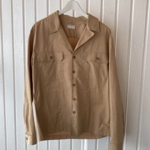 Tiger of Sweden overshirt  - Beige overshirt från Tiger of Sweden i safari-stil. Toppskick och väldigt fin kvalité. Använd ca 2ggr. Boxig och rymlig i modellen, storlek M.  Behöver rensa garderoben så jag kan göra plats för ännu mer dyra kläder jag aldrig kommer använda 🫠