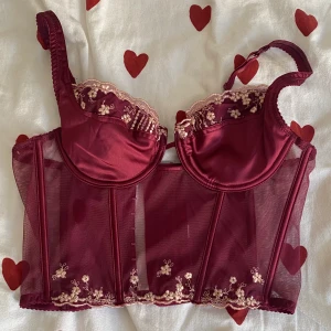 Vinröd blommig korsett! - En så snygg vinröd korsett med broderade blommor. Passar nog bäst xs/s, eventuellt en liten m. I perfekt skick då den endast använts en gång. Säljer då jag ej fått användning för den.