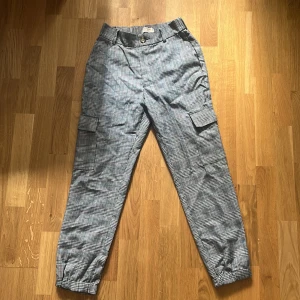 Rutiga Byxor - Säljer dessa rutiga cargo/kostymbyxor från Pull & Bear. Relativt tighta, men ändå lite baggy. Kan klä upp dem eller klä ner dem beroende på stilen man är ute efter. Storlek Medium (M)