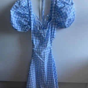 Gullig sommarklänning - Gullig rutig sommarklänning. Öppenryggad och visar sidan av kroppen, vädligt fin på om man inte är blyg. Aldrig använd då den är lite för kort för mig. Står S men en XS? Lite puffarmar