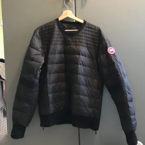 Svart Canada Goose pullover jacka - En svart Canada goose pullover jacka i fint skick, bra att under en regnjacka eller väst när det är riktigt kallt.