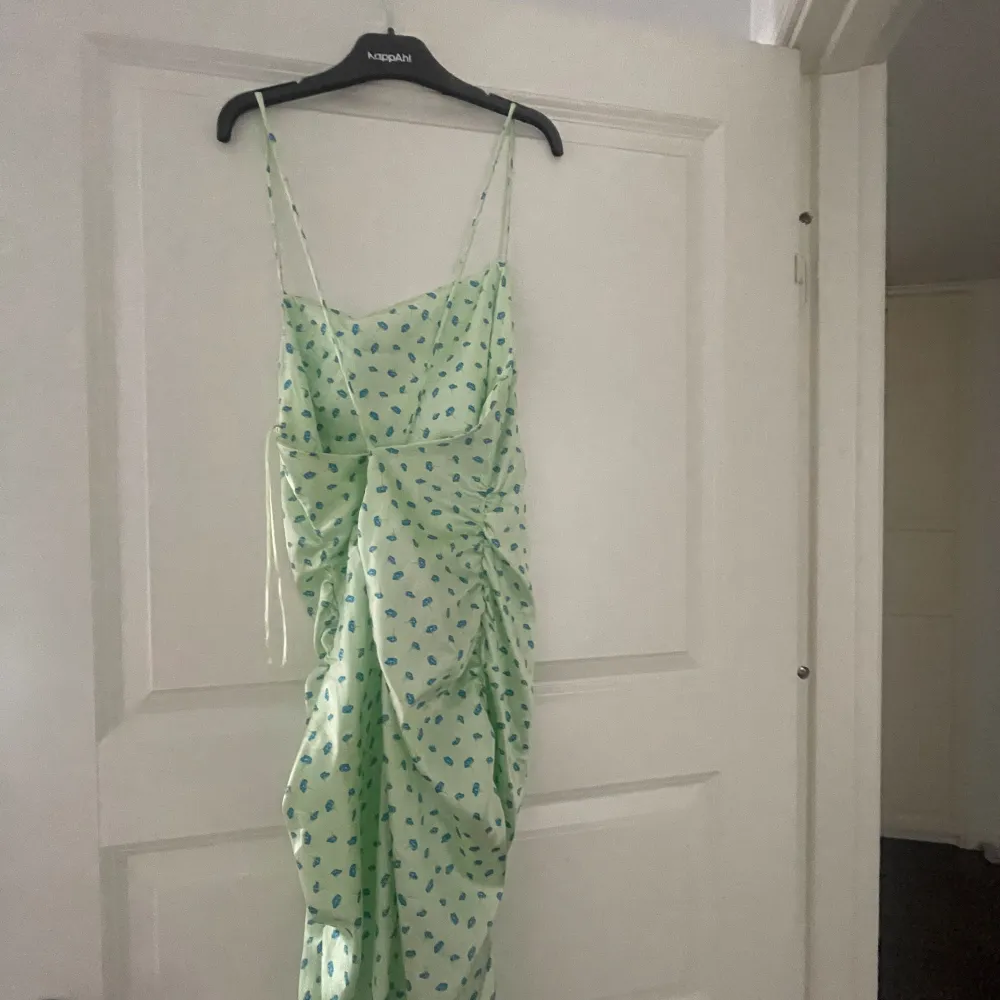 Ljusgrön midi klänning med scrunch på sidorna och slits samt små blå blommor  Endast använd två gånger. Klänningar.