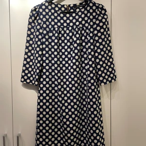 Festklänning kort modell  - Snygg rak twiggy festklänning i viskos. Rynk på bröstet lite kortare ärm. Snygg dragkedja baktill 