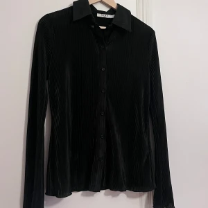 Reflad satinskjorta med vida armar  - Svart, reflad/randig skjorta i satin! Lite figursydd, Supermjuk och skön! Vida ärmar och som diskreta volanger nedtill!  Knappt använd!  Xs men den är stor i storleken! Jag skulle säga att den är mer som en s/m 