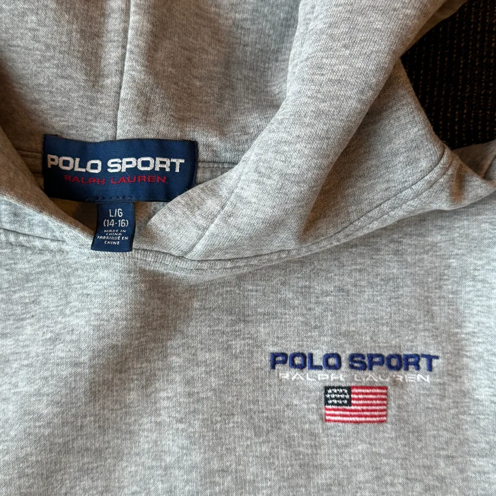 Supersnygg grå Polo hoodie som ser ut som ny. Stl L/G (14-16 år) men passar mer S/M. Ena muddens nederkant trasig, därav priset. Kan skicka foto på det. Unisex.. Hoodies.