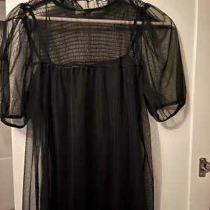 Svart klänning med underklänning - Svart klänning med genomskinligt material och tajt underklänning, använd fåtal gånger! Går till knäna på mig som är 165