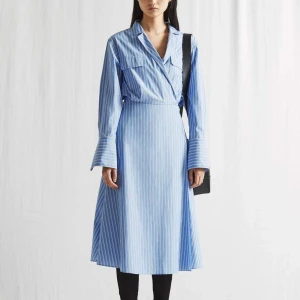 Arket shirt dress  -  Den här långärmade skjortklänningen är gjord av bomull och är designad med en omlottfunktion och en knytdetalj i midjan. Använd knappt och har bra skick inga fläckar. 