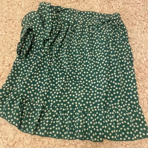 Kjol - Säljer en kjol i grön färg med vita blommor som detalj! Superfin till sommaren! 💚