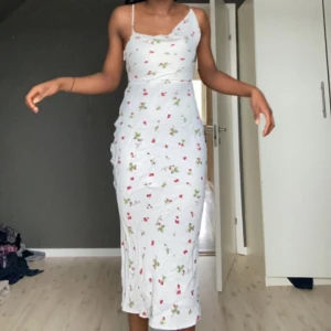 Vit klänning med draperad krage och ros detaljer. - En unik asymmetrisk draperad klänning med fin färg och bra silkes material. Köpt i Malaga, Spanien och änvänd två gånger sedan dess. 