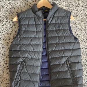 Ralph Lauren Väst - En grå ralph lauren  väst i 9/10 skick. Inga fel alls på den. Den är i barnstorlek L men passar bra på mig som är 180. Pris ej suttet i sten 😁