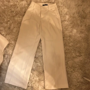 Vita kostymbyxor - Ett par vita kostymbyxor från Gina Tricot. De är i storlek XS men skulle kunna funka som storlek S också pga den vida passformen. Väldigt bra skick, har bara används en gång.
