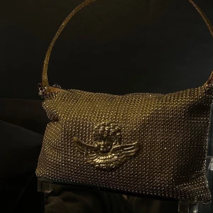 Guldväska med gulddetaljer - Stellic Design UF💫 Guld väska med diamanter och guld ängel! Skick: Mycket bra! 
