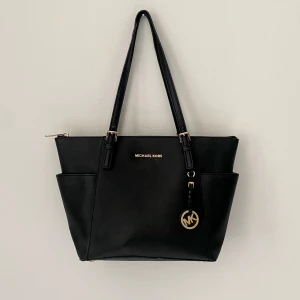 Michael Kors väska - Jättefin Michael Kors väska som tyvärr inte kmr till användning längre. Den är äkta. Använd men inga större märkbara defekter. Ett av inspännigshålen är lite slitet, se bild 3. Nypris runt 3000 kr. 