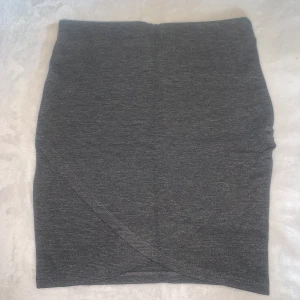 Kjol  - En snygg mörk grå tygkjol med omlott. 