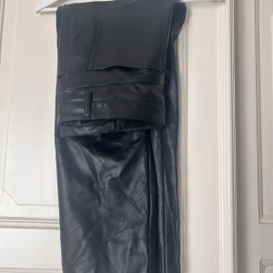 Svarta läderbyxor - Svarta byxor i läderimitation, ankellånga.