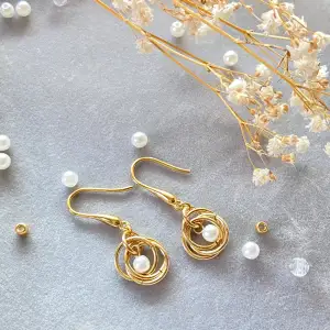 Hemgjorda örhängen med unik design av ringar o pälor som gör dig fin och söt!  Materials: Imitation pearls (acrylic); Gold plated on brass rings and ear hooks 