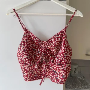 Blommig topp - Jättesöt blommig topp, går att knyta där framme. Aldrig använd så nyskick.