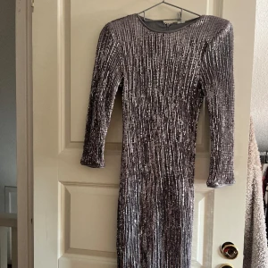 Klänning från Nelly  - Jag vill sälja denna jättefina klänningen från Nelly. Den är i helt nyskick och har inga tecken på användning. Den är svart och silvrig och glittrig.💕