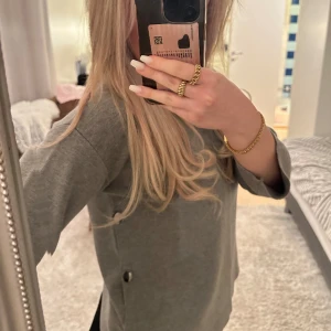 Tröja - En jättefin grå tröja med fina detaljer, den är även hög i krage. Storlek S.