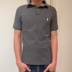 Ralph lauren pike - Nu säljer vi en Ralph lauren piké i färgen grå som är i ett skick som nytt. Den har bara blivit använd 1/2 gånger innan bilderna togs. Perfekt pike nu inför våren och sommaren. Priset går att diskutera vid snabb affär. 