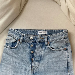 Jeans från Zara - Skitsnygga jeans från Zara, ljusa, med silver knäppning och ”klippta” nertill. Mindre slitage vid ljumsken som behövs lagas så småningom. 