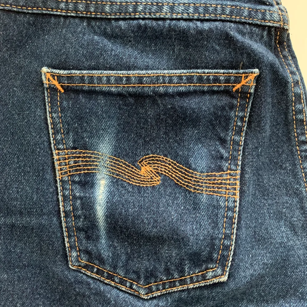 Perfekta raka mörkblå jeans från Nudie Jeans. Jeansen är i bra skick, endast använda ett fåtal gånger. Jeansen är i storlek midja 28 och längd 32cm. Har en liten skada på vänster bakficka. Ursprungligt pris: 1400 SEK Obs: köparen står för frakten!. Jeans & Byxor.