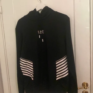 EA7 tränings hoodie - Säljer nu denna EA7 hoodie som är i tränings material den har aldrig kommit till användning Köpt på NK i Göteborg stl M om ni har några frågor hör av er