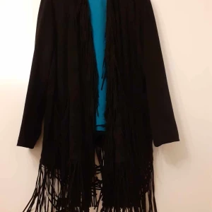 Öppen tunn "jacka" - Jacka i 92% polyester & 8% elastan, mockakänsla. Öppen modell med fransar från hals & ner plus fransar på fickorna. Stl 54/56, använd en gång så som nyskick. Snyggt tyg som faller fint. 