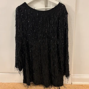 Glittrig klänning - Oversize klänning med djup rygg och glittriga fransar från Bikbok. Aldrig använd.