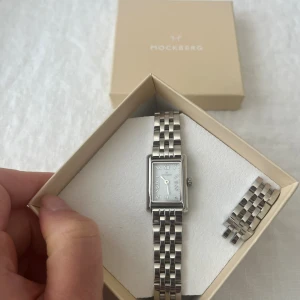Mockberg Timeless silver klocka  - Klocka från mockberg i silver. Klockan har använts sparsamt. Inga repor på urtavla. Minimal slitning på länk. Extra länkar medföljer och box.  Mer info om klockan här😊 https://mockberg.com/products/timeless-silver?_gl=1*16pv4i3*_up*MQ..&gclid=CjwKCAj