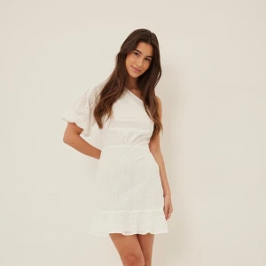 Vit klänning - Säljer denna fina och slutsålda klänning från NA-KD. Miniklänning med en one-shoulder- look. Helt ny med lapparna kvar!!!🩷😁😁