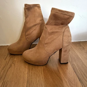 Platform stövletter storlek 38 - Platform-stövletter i Faux mocka, storlek 38, normal i storleken. Camel-färgade. Aldrig använda. Klackhöjd 11 cm inkl platå.