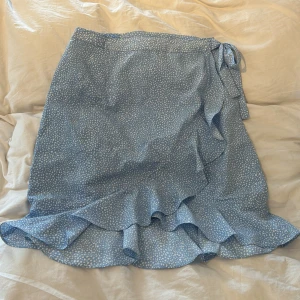 Omlott kjol - Söt omlott kjol med vita ”prickar” i en härlig ljusblå färg!  Använd men i superfint skick🌟 Säljer då jag inte riktigt gillar längden 