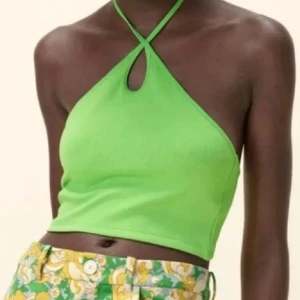 Grön halterneck topp - En grön halterneck topp med korsade band framtill och knytning i nacken. Toppen är croppad och ärmlös, vilket gör den perfekt för varma sommardagar.