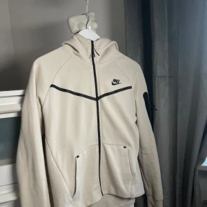 Nike (HEL) tracksuit ”Creamy Vanilla - (Bra skick) - på både byxorna och jackan.           Det är ett litet fläck på ena armen som man knappst kan se, också går bort genom att tvätta den.  Ny pris (1900)  Jag säljer den pågrund av att den är för lite för mig 