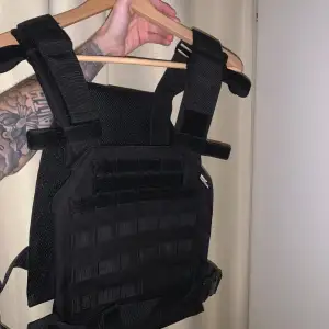 ”Tactical” väst som ser ut som en skyddsväst.  Perfekt för träning eller som ett fashion statement Svart / black. Fraktas med Postnord över hela Sverige eller hämtas på plats.