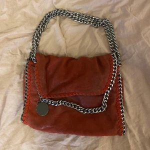 Stella liknande väska  - Super fin röd väska! Knäppet på väskan är väldigt trasig ( se bild 3) där av priset men går fortrande att stänga. Går även att ha som långt band 