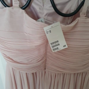 Klänning för sommarens alla fester! - Jättefin ljusrosa klänning perfekt för stidenten, balen, bröllop eller andra sommarfester! Axelbanden går att ta bort och klänningen sitter bra på plats med silikonband på insidan av klänningen. I strl 42. 