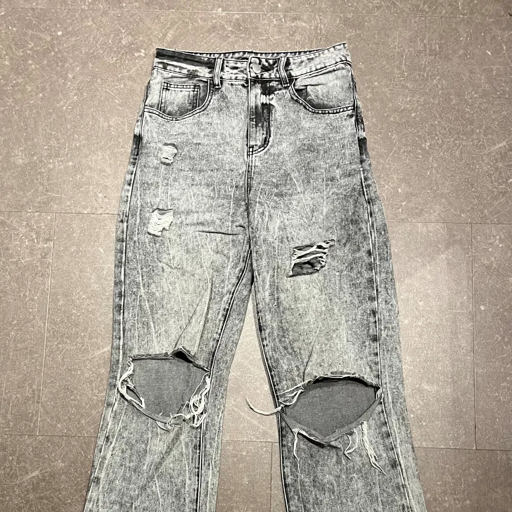Ett par gråa jeans i storlek 36. Modellen på dessa är straight. Skulle säga att de är ganska high-waist. Även dessa har hål vid knäna som ger en lite street-ig look. Ganska väl använda men i bra skick. Litet hål mellan benen, men syns ej när de är på. Jeans & Byxor.