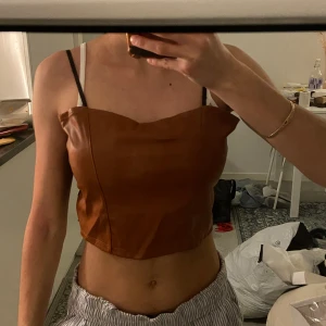 Brun läder top - Snygg topp i fake brun läder på framsidan och spets på baksidan. Aldrig använt 