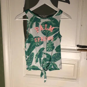 Vitt linne med gröna blad på - Ett fint vitt linne med gröna växter och rosa text på med bra skick 💗 Liten för sin storlek.