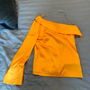 One-shoulder Satinblus  - Superfin satinblus med one-shoulder från NA-KD ca 2 år gammal. Använd vid ett tillfälle så helt som ny! Superfin på och bekväm