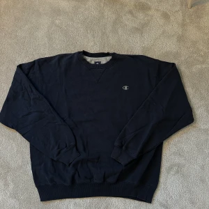 Vintage Champion Sweater - Tröjan är från 90 talet men skicket är trotts det väldigt fint, utöver en sömn som gått upp på under armen (syns inte när man bär tröjan), det går även fixa rätt lätt om man syr.  Markerad som Xl men sitter som Baggy M.