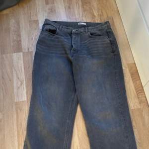 Gråa högmidjade jeans från Gina Tricot nergångna längst ned på benen