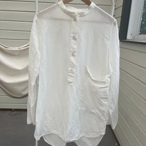 COS linneblus linneskjorta Storlek M inne lin bomull - Vit krispig blus/skjorta från COS i 71% linne 29% bomull. Finns några pyttesmå stänk/fläckar jag ej testat att ta bort på sidan av ryggen och nedtill fram.  Ärmhåla till ärmhåla 58cm Innerärm 47cm Längd 77/84 cm (längre bak) 