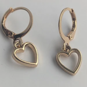 Guldörhängen med hjärtformade hängen - Ett par eleganta örhängen i guld med hjärtformade hängen. Örhängena har en enkel och stilren design med små hjärtan som hänger från en rund ögla.