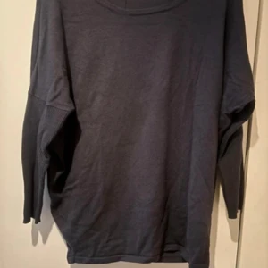 Mörkblå tröja från Saint Tropez - En mörkblå tröja från Saint Tropez med långa ärmar och en rund halsringning. Tröjan har en lös passform och är tillverkad i ett mjukt material.är lite nopprig