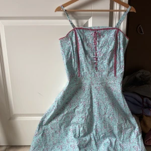 Klänning -  Drömigaste klänningen med blommor som är helt perfekt till sommaren 🌺 Korsett överdel med rosa snören man knyter till rosett 🎀 Jättefina detaljer!  Nyttskick då jag endast har använt 1 gång💓