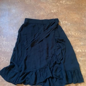 Svart söt kjol - En svart knä lång kjol, kan knytas från sidan, elastisk midja.